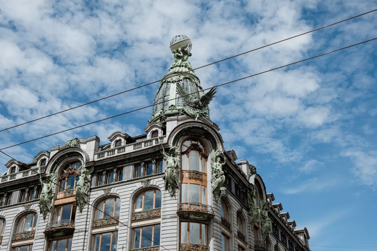 Fachada ornamentada de edifício em estilo Art Nouveau com janelas curvas e detalhes esculpidos sob um céu azul em Bruxelas.