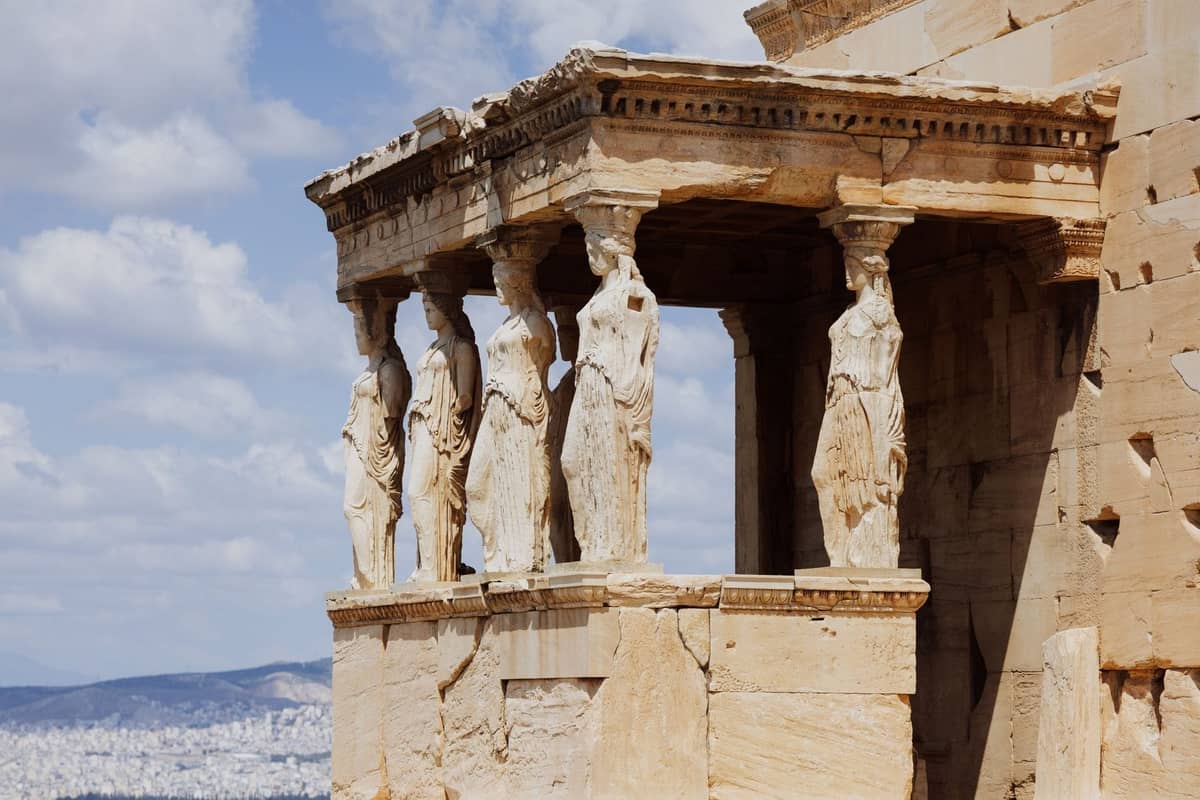Nahaufnahme des Erechtheion mit seiner berühmten Karyatidenvorhalle auf der Akropolis in Athen, Stadtbild im Hintergrund.