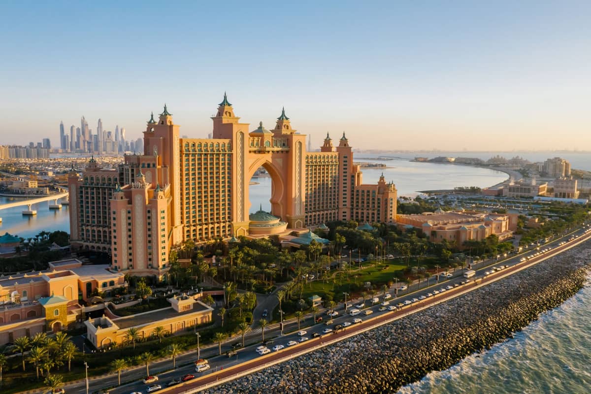 Weitläufige Luftaufnahme des Atlantis, The Palm Resorts auf der Palm Jumeirah in Dubai – mit dem ikonischen rosafarbenen Hotel, den gepflegten Außenanlagen, dem umgebenden Wasser und der Skyline der Stadt im Hintergrund.