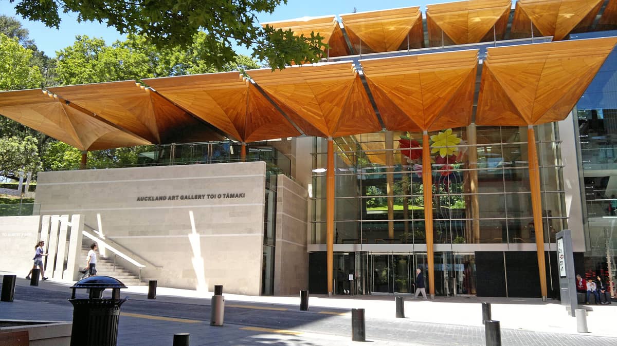 Der Haupteingang der Auckland Art Gallery Toi o Tāmaki mit modernen Holzvordächern, großen Glasfenstern und dem gut sichtbaren Schriftzug der Galerie.