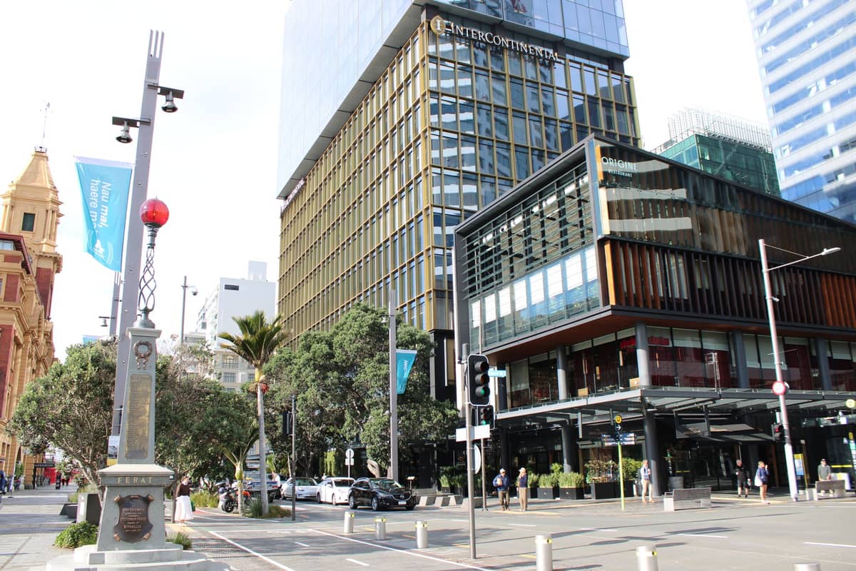 Downtown Auckland street scene with public art sculpture and modern glass buildings in the background.