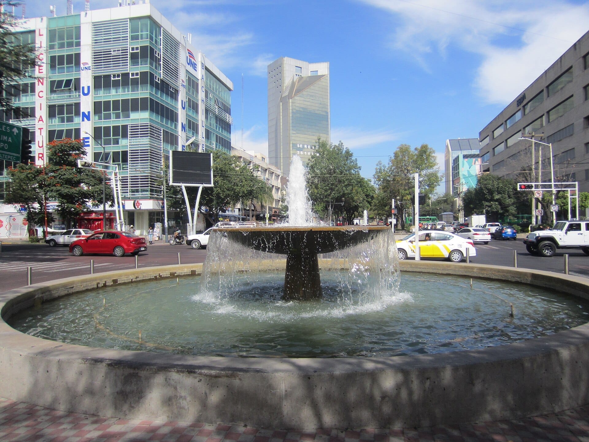 Fontana con acqua a cascata al centro dell'Avenida Chapultepec, circondata da moderni edifici per uffici e traffico urbano a Guadalajara.