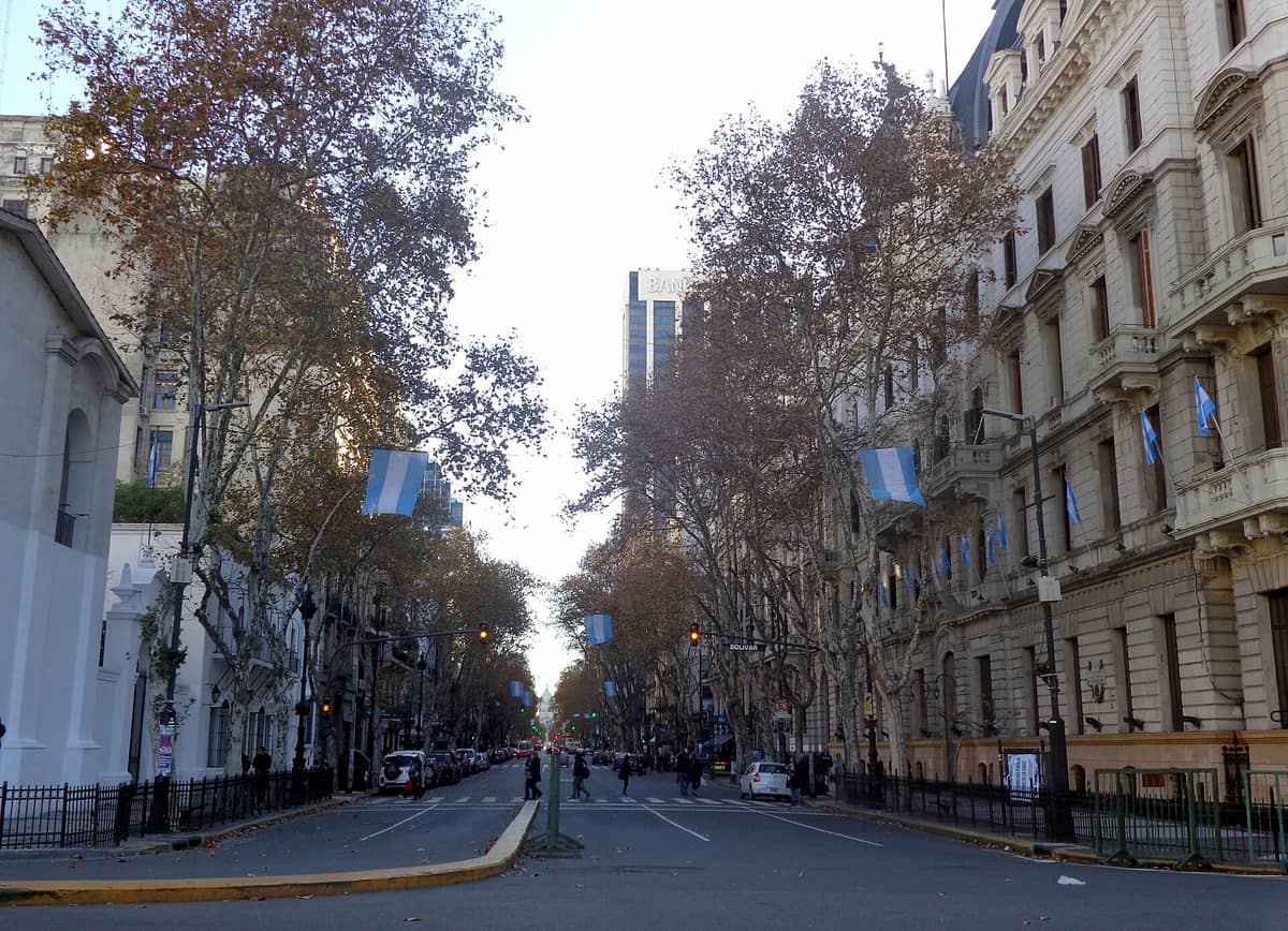 มุมมอง Avenida de Mayo ในบัวโนสไอเรส อาคารประวัติศาสตร์ ต้นไม้สองข้าง ถักธงชาติอาร์เจนตินา กับผู้คนเดินบนถนนกว้าง
