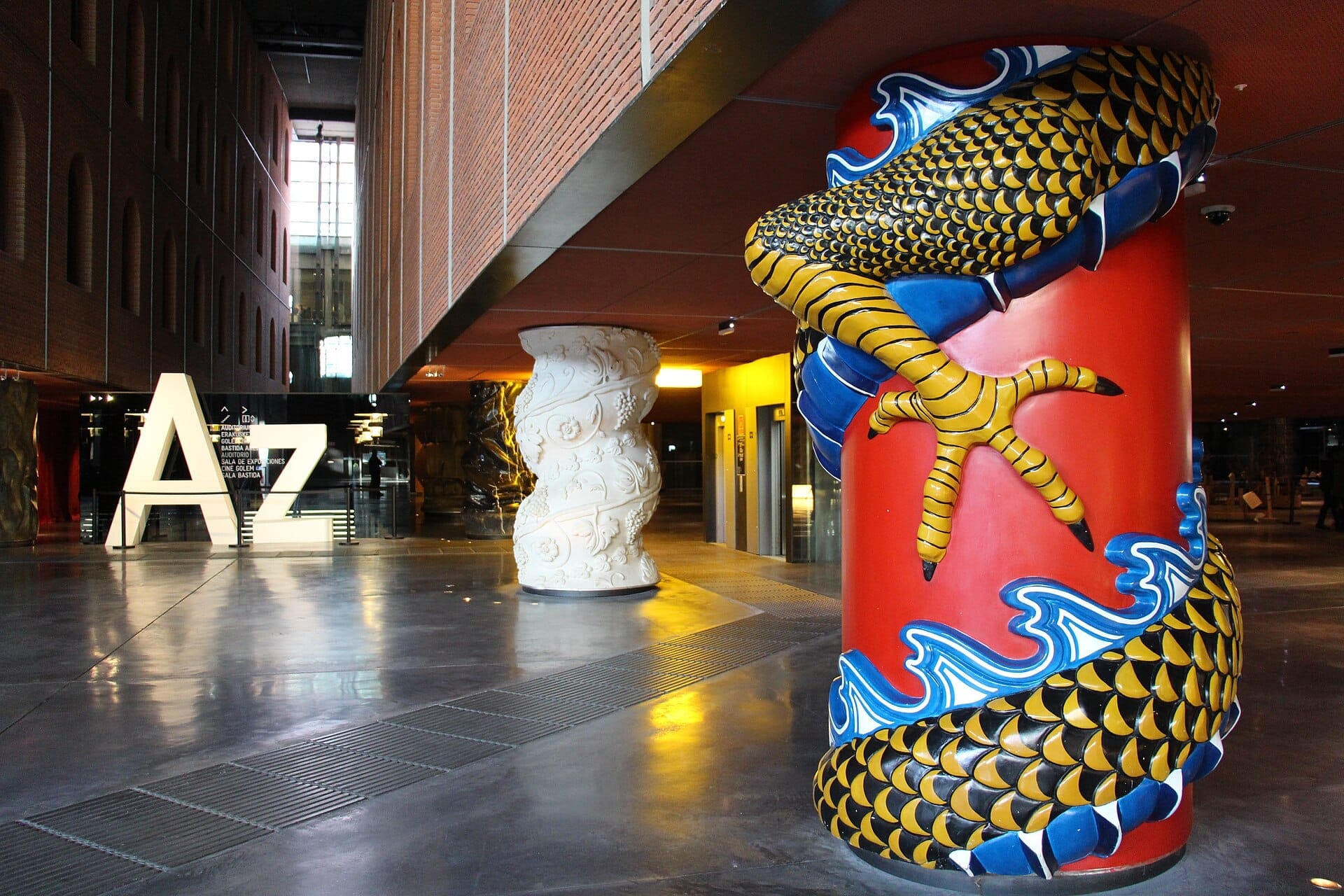 Interior view of Azkuna Zentroa in Bilbao, featuring artistically decorated columns, shiny floors, and large illuminated 'Az' letters.