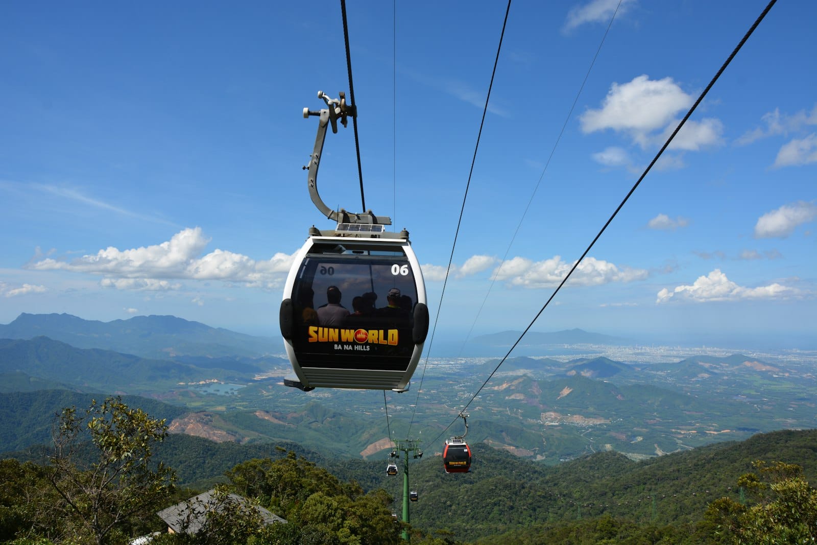 กระเช้าไฟฟ้าที่มีชื่อ 'Sun World Ba Na Hills' กำลังขึ้นเหนือภูเขาสีเขียวพร้อมทิวทัศน์สวยงามและท้องฟ้าสีฟ้าที่ดานัง