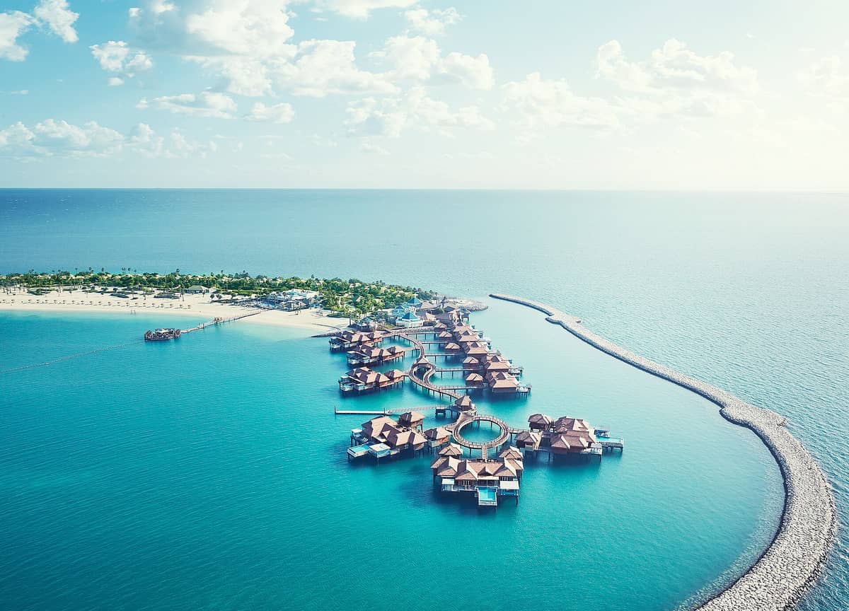 Luftaufnahme des Banana Island Resort Doha by Anantara mit Overwater-Villen, Sandstränden und türkisfarbenem Wasser auf einer Privatinsel.