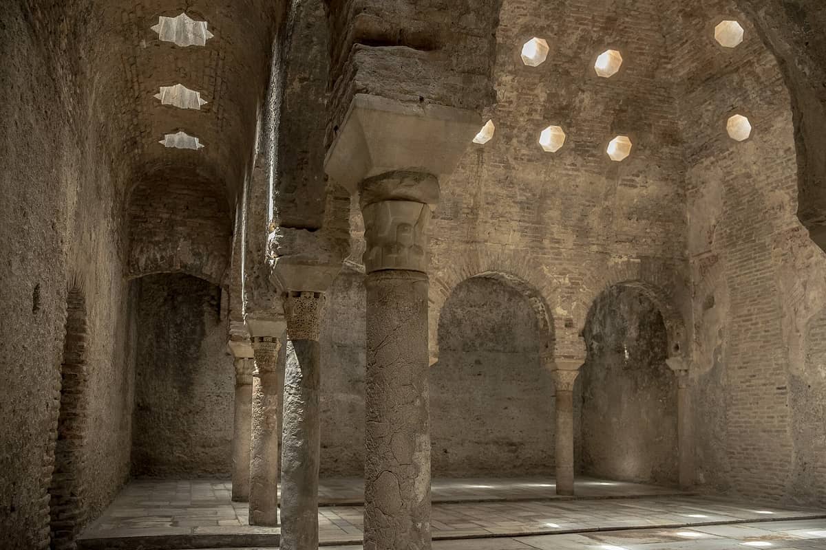 ภายใน El Bañuelo ในเมือง Granada แสดงให้เห็นเสาหิน โค้งอิฐ และช่องแสงรูปดาวที่ส่องสว่างให้แก่โรงอาบน้ำสไตล์มัวร์ที่ได้รับการอนุรักษ์ไว้