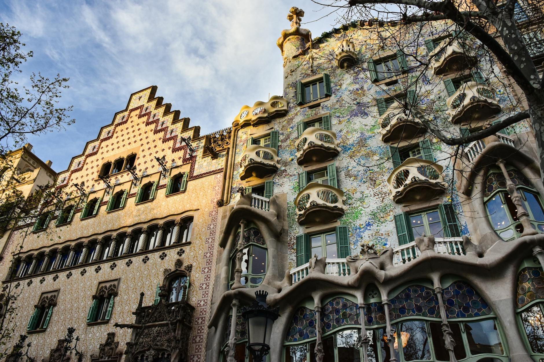 Iconic facade of Casa Batlló and neighboring building in Barcelona, with striking architecture clearly visible and evening light creating an atmospheric scene.