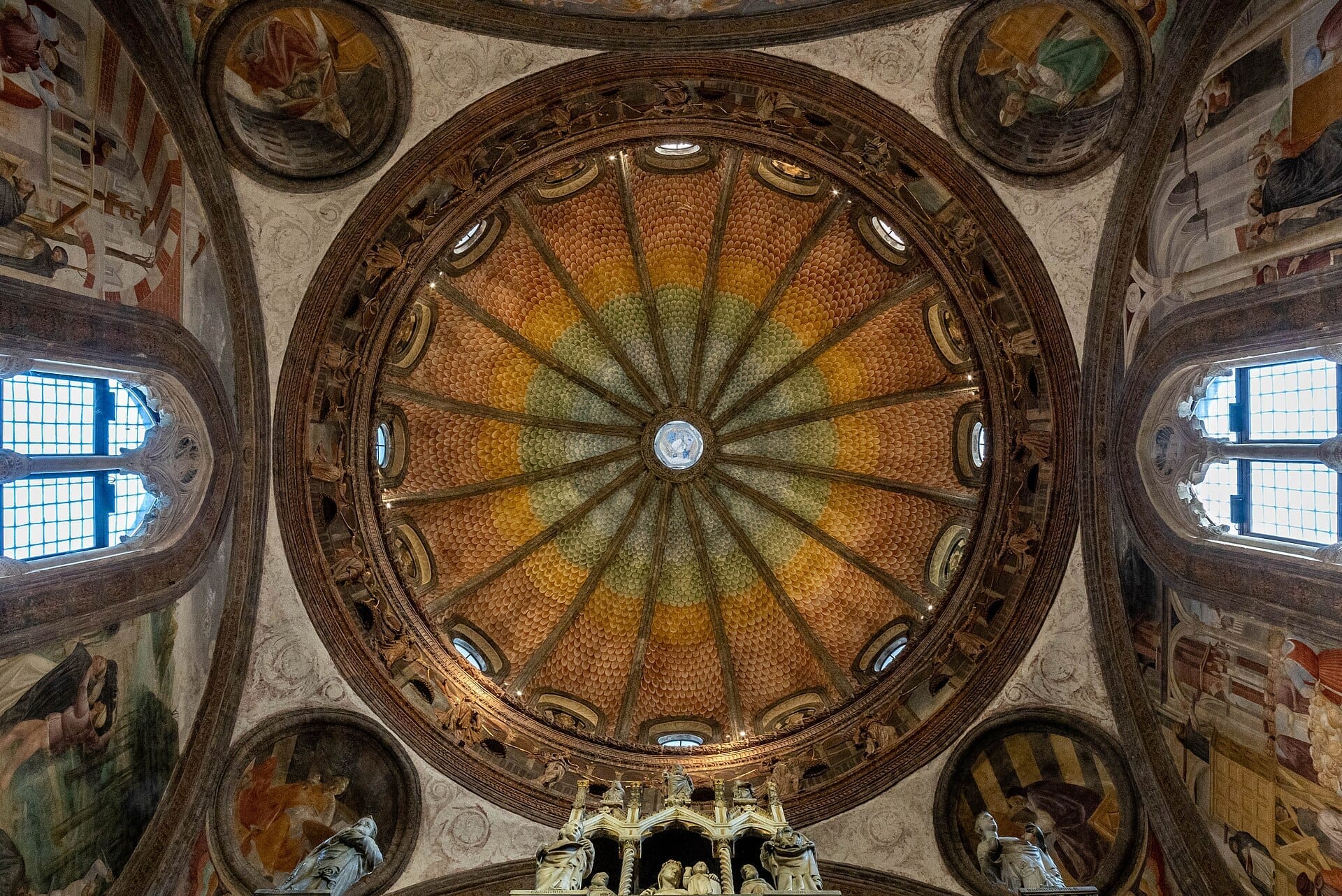 Vista dettagliata della vivace cupola rinascimentale e degli affreschi all'interno della Basilica di Sant'Eustorgio a Milano, con luce naturale che filtra dalle finestre ad arco.