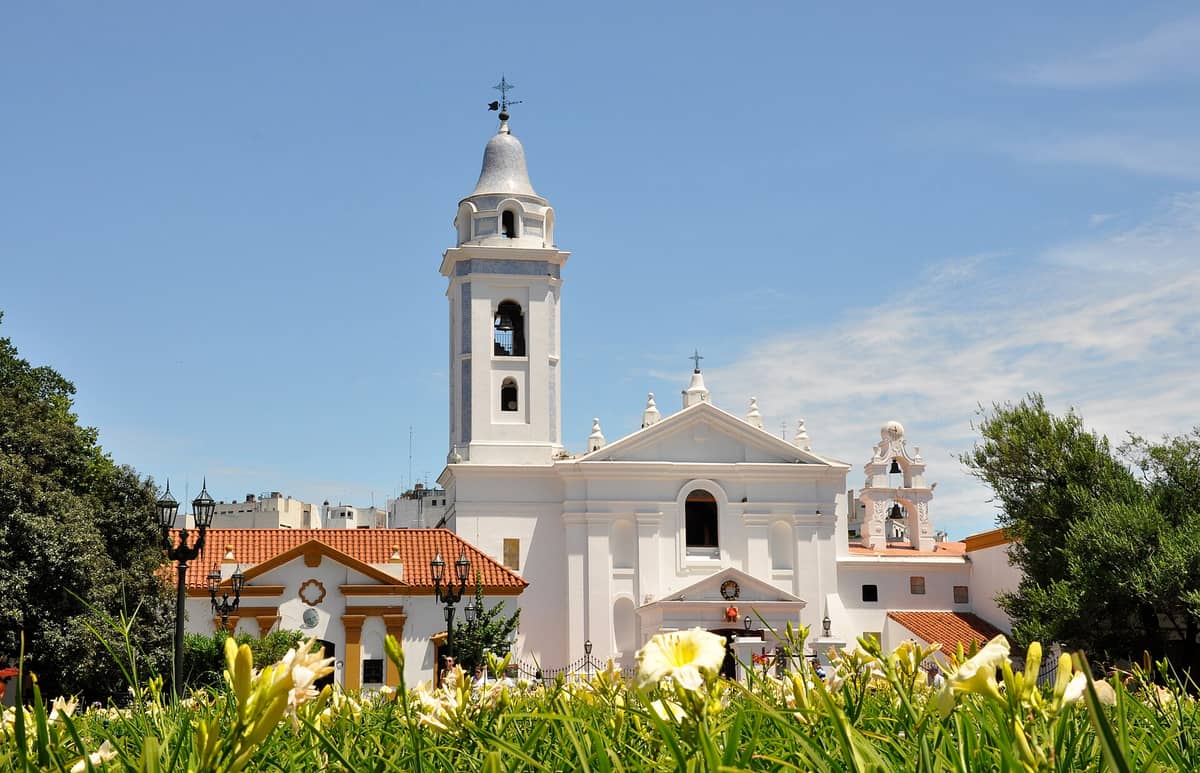 มุมมองภายนอกของ Basílica Nuestra Señora del Pilar ในย่านเรโคเลตา บัวโนสไอเรส มีผนังสีขาวสไตล์ยุคอาณานิคมและหอระฆังบนท้องฟ้าใส