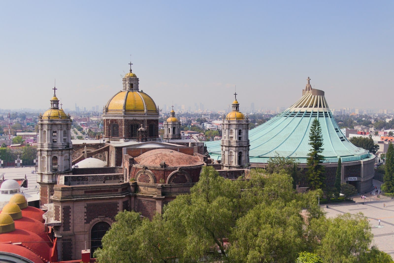 Vista aerea della Vecchia e della Nuova Basilica di Nostra Signora di Guadalupe a Città del Messico, con chiese a cupola e il panorama urbano sullo sfondo.