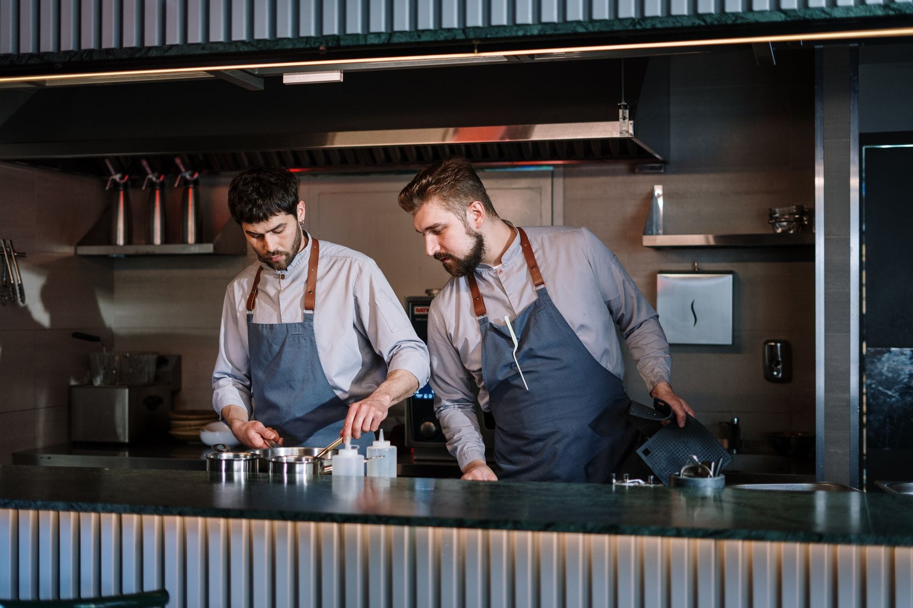 Due chef in una moderna cucina aperta che impiattano il cibo, mettendo in evidenza l'esperienza culinaria e l'innovazione.