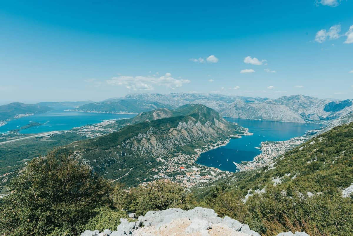 Wide panoramic view of Kotor Bay with dramatic mountains, blue water, and the town of Kotor visible, perfectly illustrating the landscape ideal for boat tours.