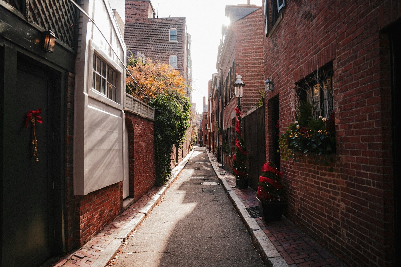 ตรอกแคบอิฐแดงที่ Beacon Hill แสงแดดส่อง ตึกแถวอิฐแดงเก่าแก่ ประตูตกแต่งและกล่องดอกไม้ ถ่ายทอดบรรยากาศที่น่าหลงใหลของย่านนี้