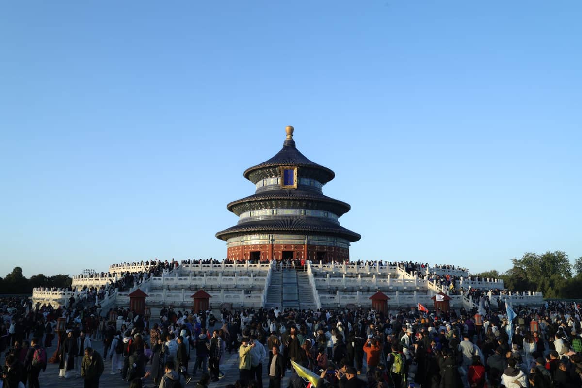 The Hall of Prayer for Good Harvests at Beijing's Temple of Heaven, crowded with visitors under a clear blue sky.