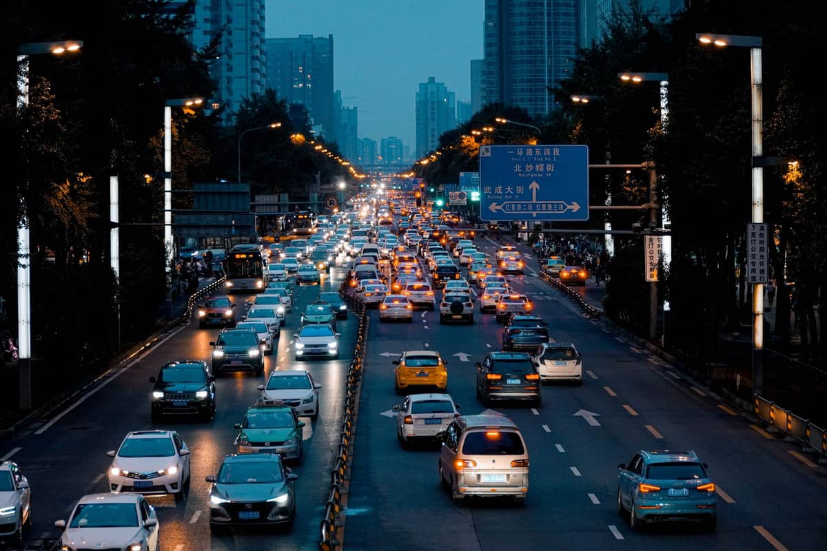 Intenso tráfico nocturno en una concurrida vía de Beijing, con letreros iluminados y edificios altos al fondo.