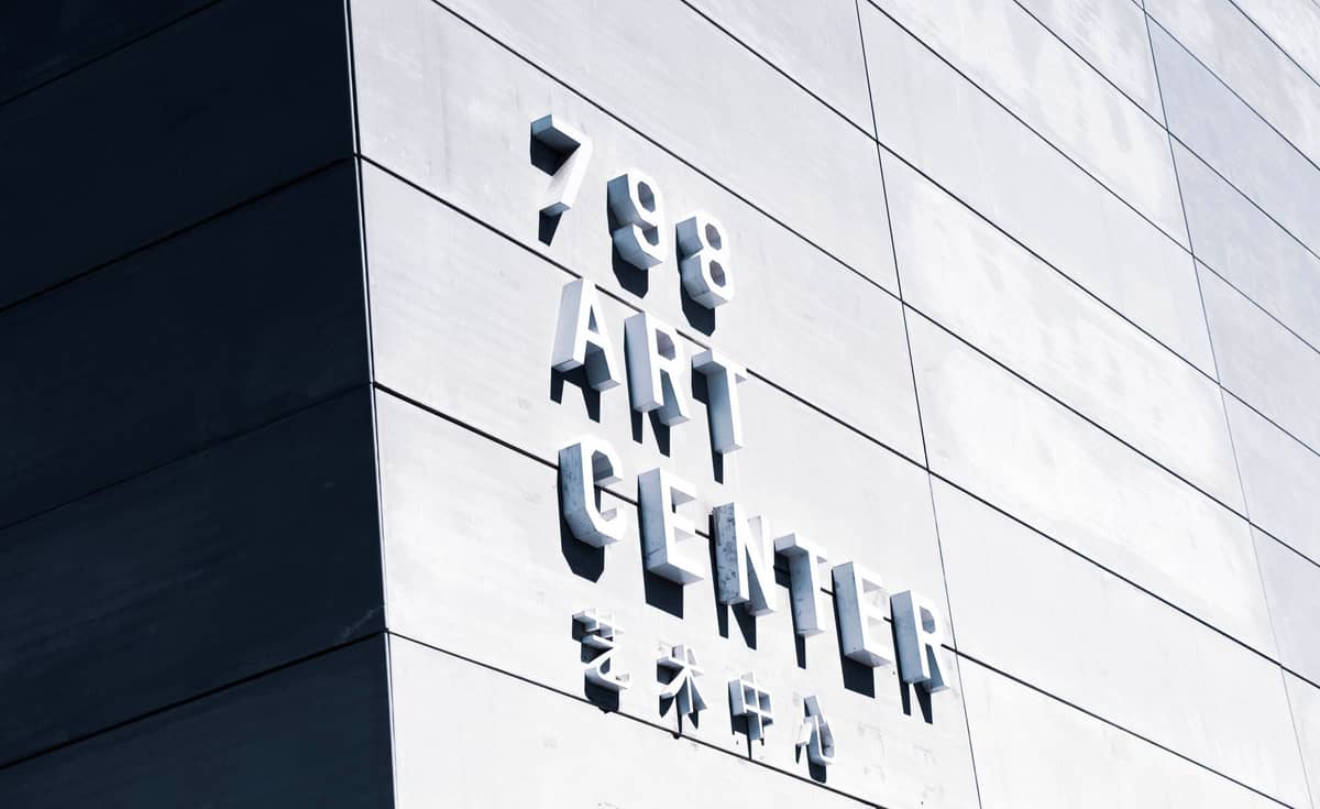 Moderne graue Wand mit erhabener Beschilderung mit der Aufschrift '798 Art Center' auf Englisch und in chinesischen Schriftzeichen.