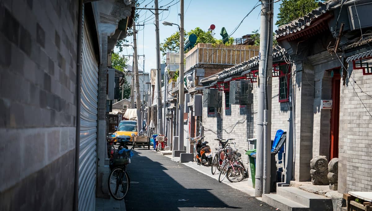 Eine schmale, ruhige Hutong-Gasse in Peking mit grauen Backsteingebäuden, Fahrrädern und alltäglichen Details – weit weg vom touristischen Trubel.
