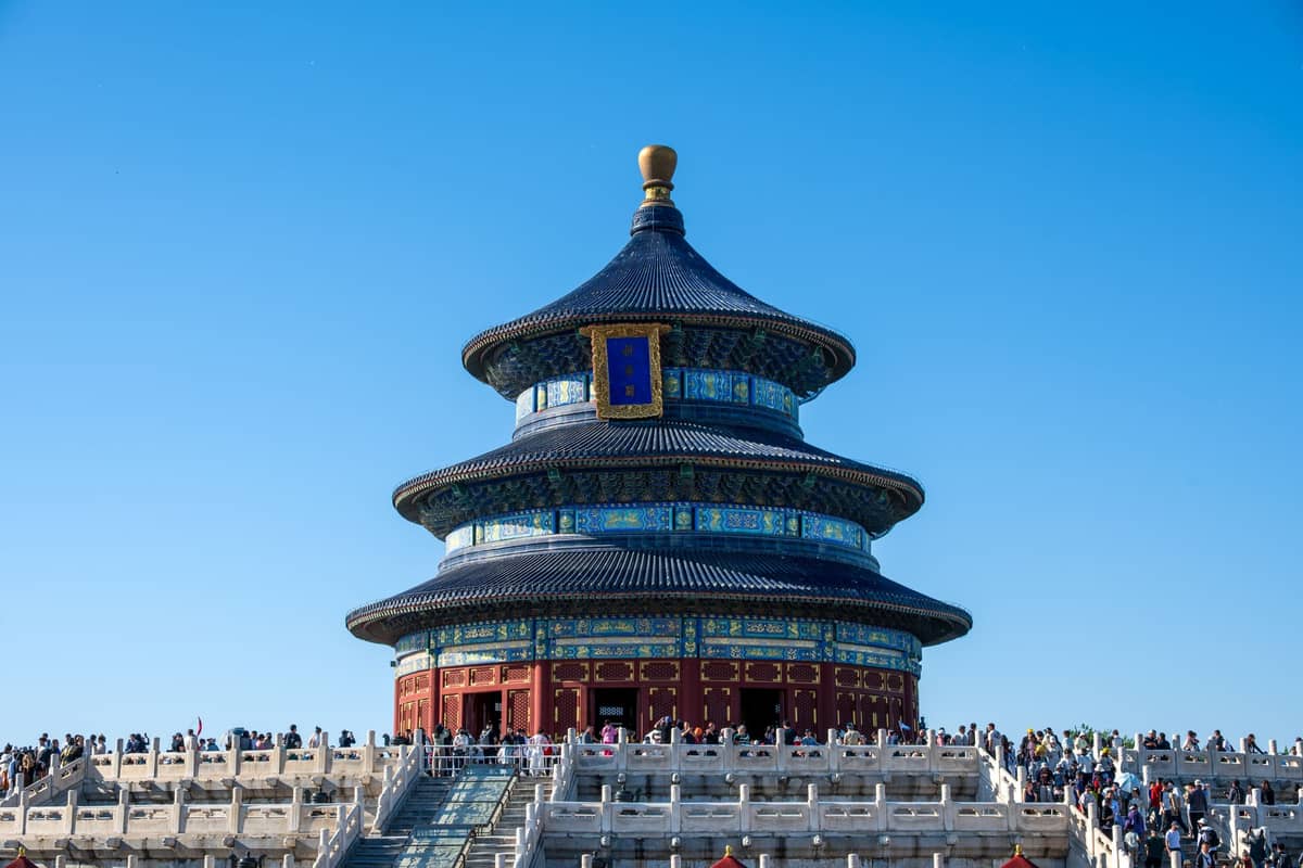 Vue panoramique du Hall de la Prière pour les Bonnes Récoltes du Temple du Ciel avec ciel bleu, détails ornés et visiteurs sur les terrasses en pierre.