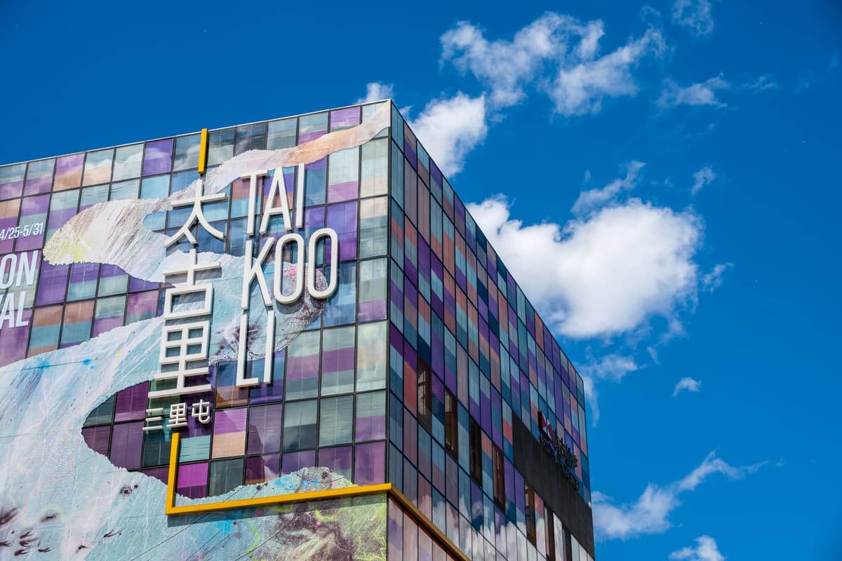 Bunte Glasfassade des Einkaufszentrums Taikoo Li Sanlitun unter blauem Himmel mit auffälliger Beschilderung und künstlerischem Design im Bezirk Chaoyang in Peking.