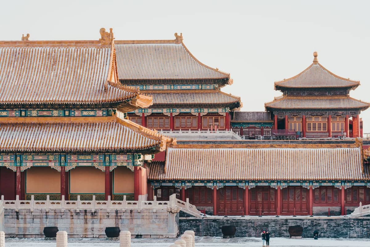 Close-up view of ornate Forbidden City palace buildings with golden roofs and red walls, iconic example of Beijing imperial architecture in sunlight.