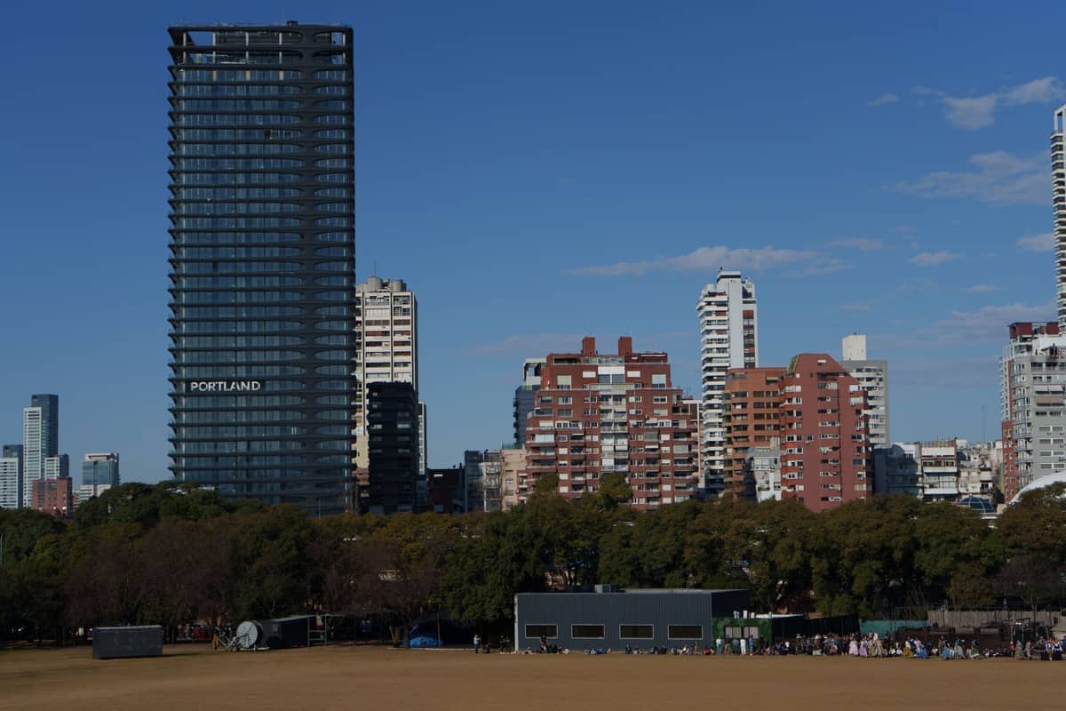 อาคารสูงสมัยใหม่และอาคารที่พักอาศัยใน Belgrano มีต้นไม้เขียวขจี ท้องฟ้าแจ่มใส มองจากสวนหรือสนามกีฬาท้องถิ่น