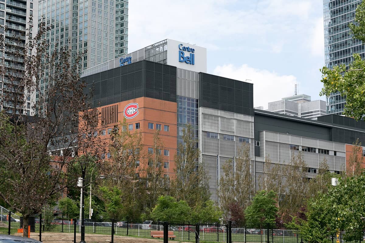 Weitwinkelpanorama des Bell Centre in Montréal mit dem markanten Schriftzug 'Centre Bell' und dem Logo der Canadiens de Montréal an der Fassade, umgeben von Hochhäusern der Innenstadt.