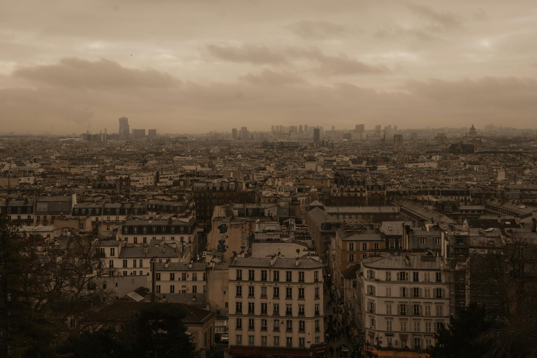 Vista panoramica sui tetti di Parigi dall'alto, sotto un cielo nuvoloso e suggestivo, che cattura l'atmosfera e la quota del quartiere di Belleville.