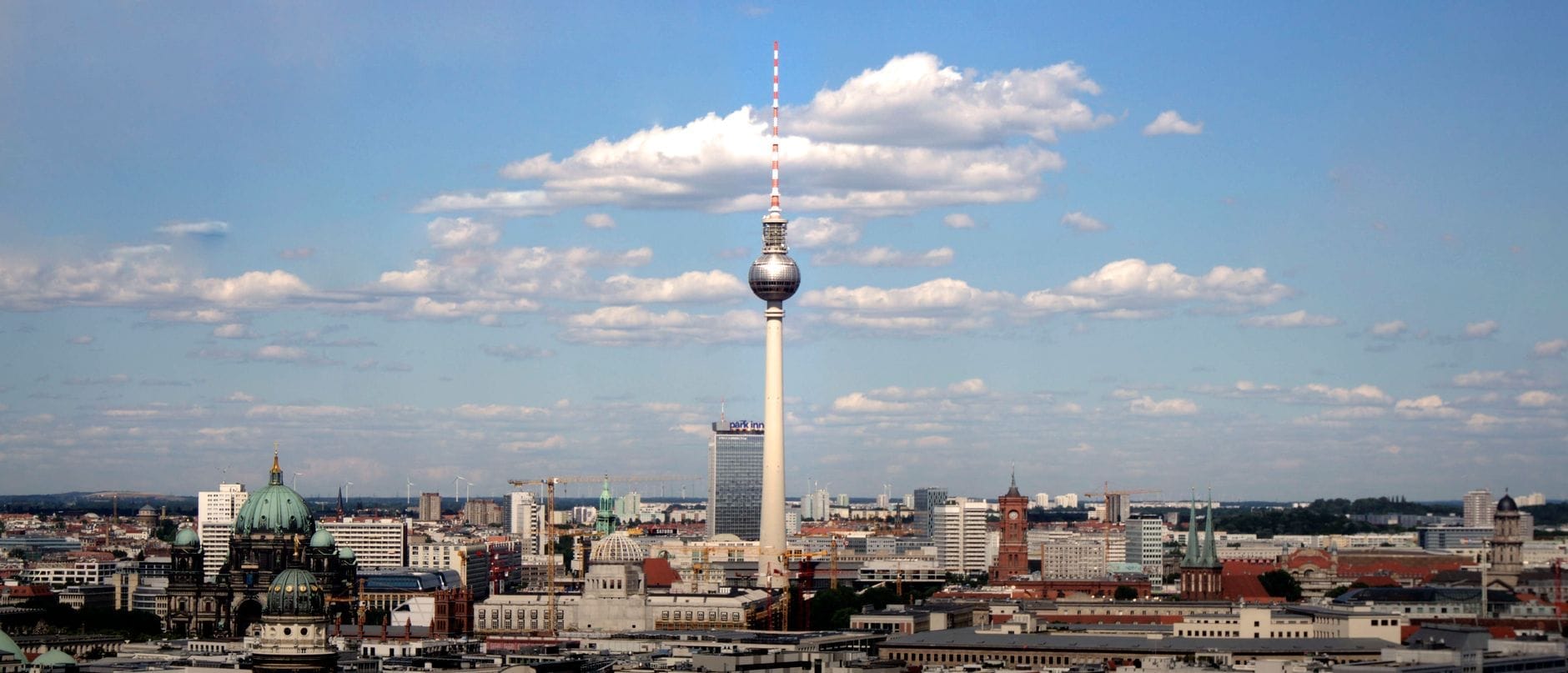 Ampia vista panoramica dello skyline di Berlino con la Torre della Televisione che si innalza imponente su un cielo azzurro con qualche nuvola sparsa.
