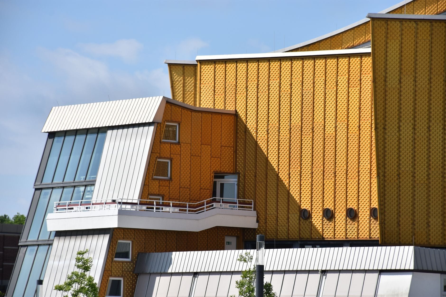 Vista ravvicinata dell'iconica facciata dorata e dell'architettura moderna dalla geometria decisa della Berliner Philharmonie in una luminosa giornata di sole.