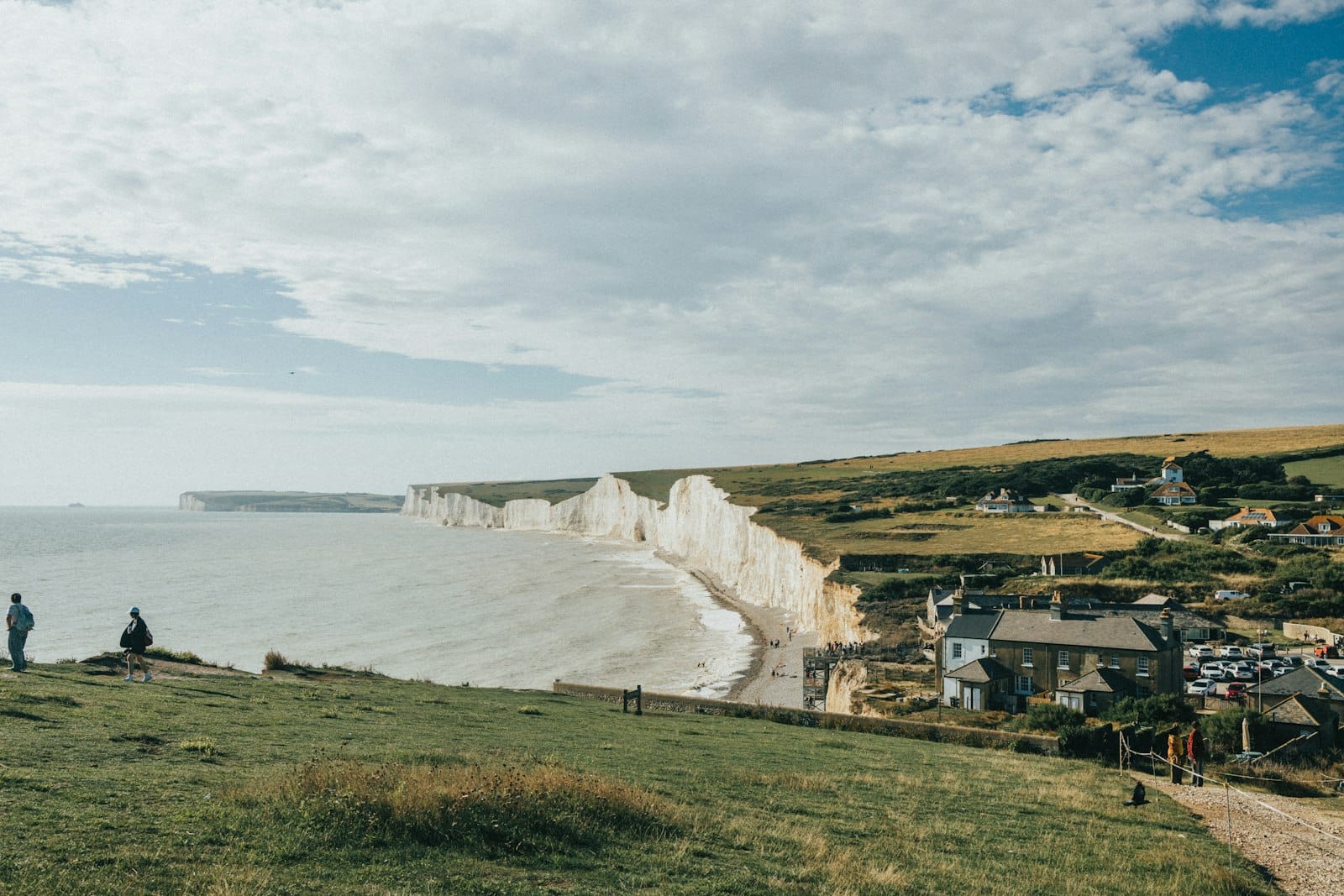 Brighton yakınlarında çarpıcı beyaz tebeşir kayalıkları ve kıyı manzaraları, çimenli tepeler, evler ve doğal manzaranın tadını çıkaran insanlar