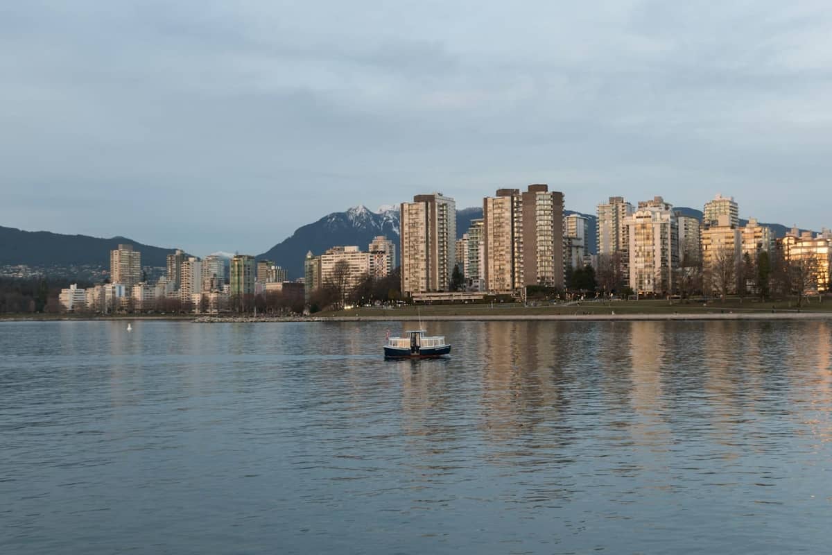 วิวเส้นขอบฟ้าของ Vancouver จากฝั่งน้ำตรงข้ามในยามพระอาทิตย์ตกดินพร้อมฉากหลังเป็นภูเขา อาคารตามแนวชายฝั่ง Kitsilano