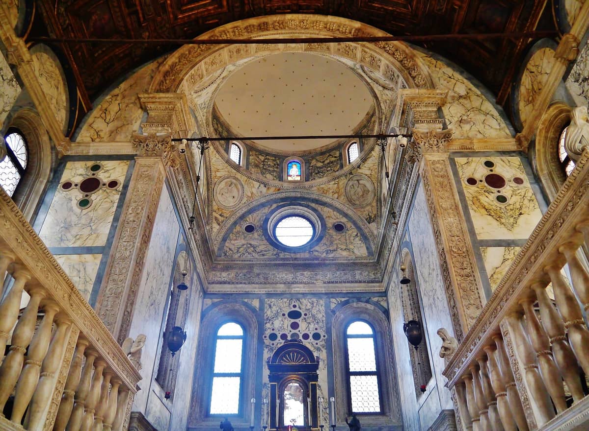 Innenraum einer venezianischen Renaissance-Kirche mit Marmorwänden, gemeißelten Rundmedaillons, Säulen und verzierten Rundfenstern, durchflutet von natürlichem Licht.