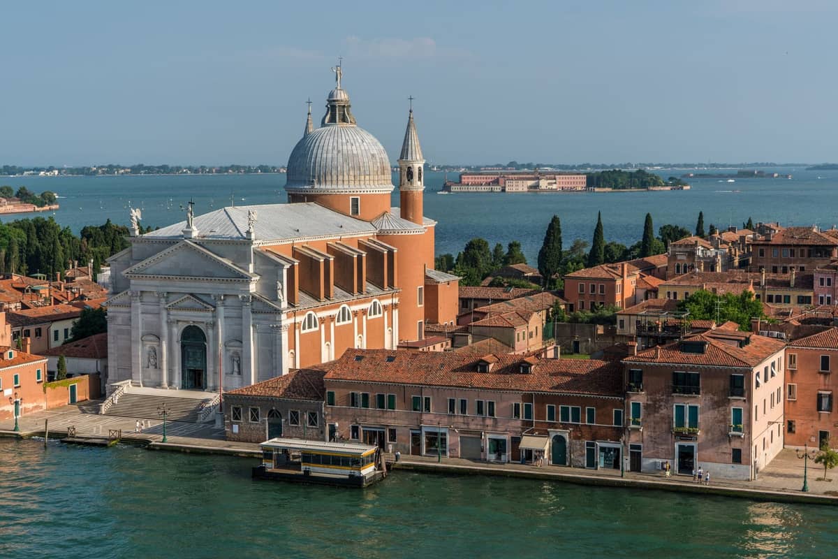 Landschaftsansicht der Chiesa di San Giorgio Maggiore, entworfen von Palladio, auf ihrer eigenen Insel in Venedig mit Wasser im Vordergrund.