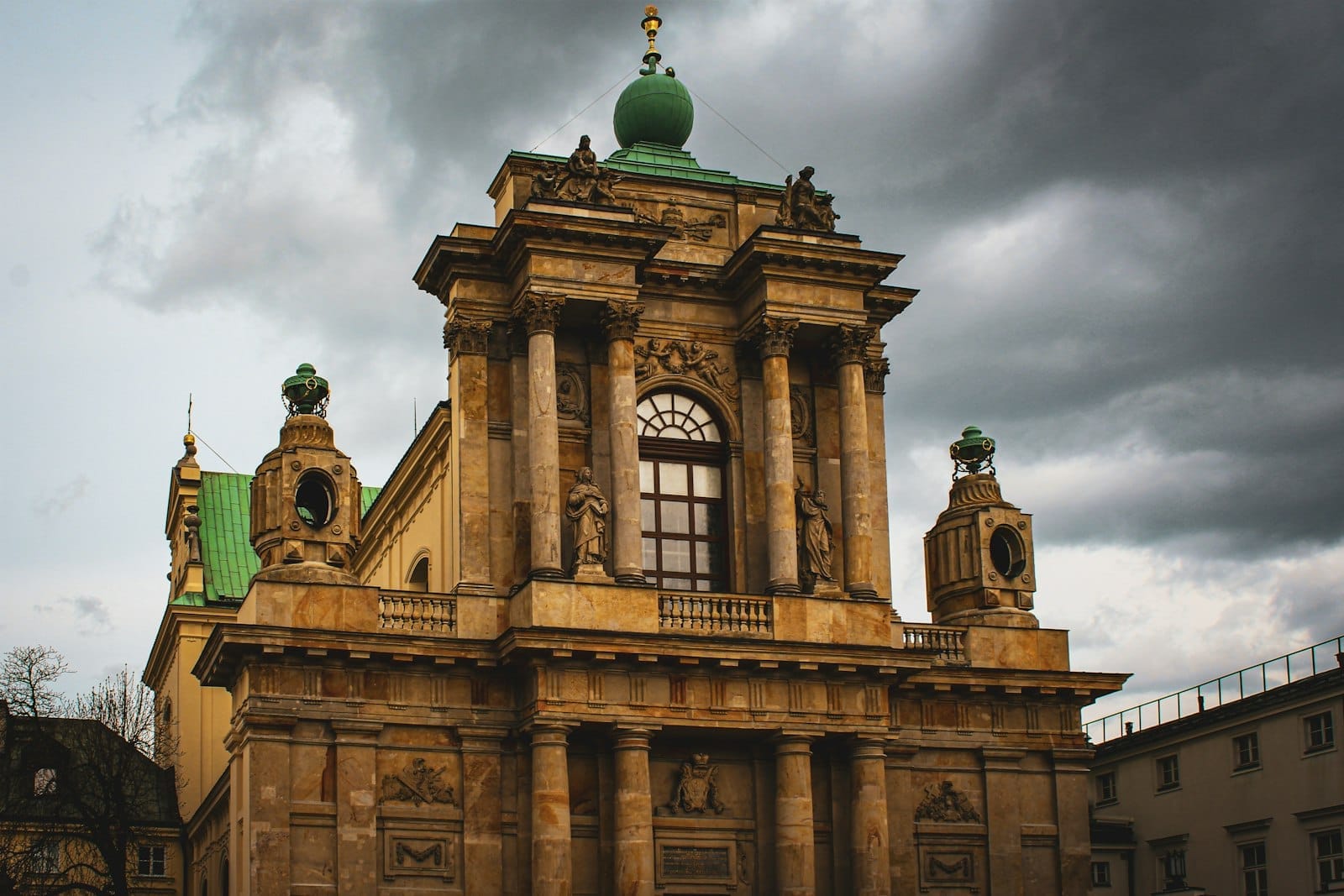 Fachada barroca de uma igreja em Varsóvia com colunas ornamentadas e estátuas, iluminação dramática sob um céu carregado, destacando a arquitetura histórica.