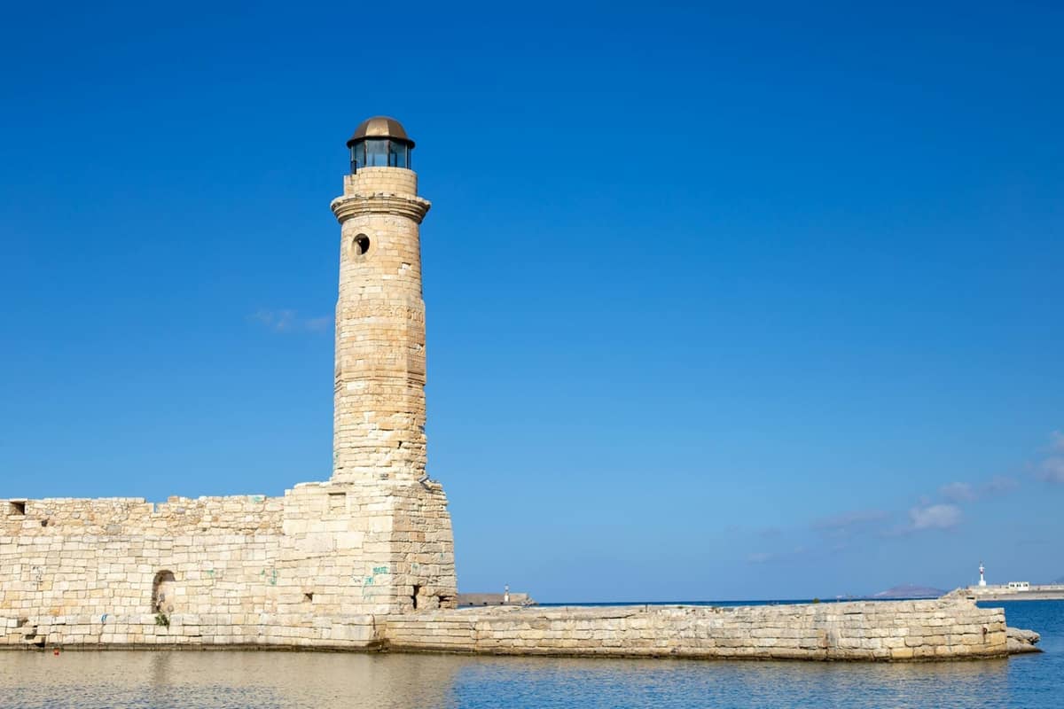 Mercusuar batu di pelabuhan Venesia Rethymno di bawah langit biru cerah, sebuah landmark terkenal yang ideal untuk perjalanan sehari dari Rethymno, Kreta.
