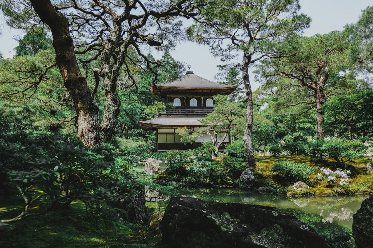 The Zen garden at Ginkaku-ji (Silver Pavilion) in Kyoto with moss, greenery, and traditional Japanese architecture surrounded by lush trees.
