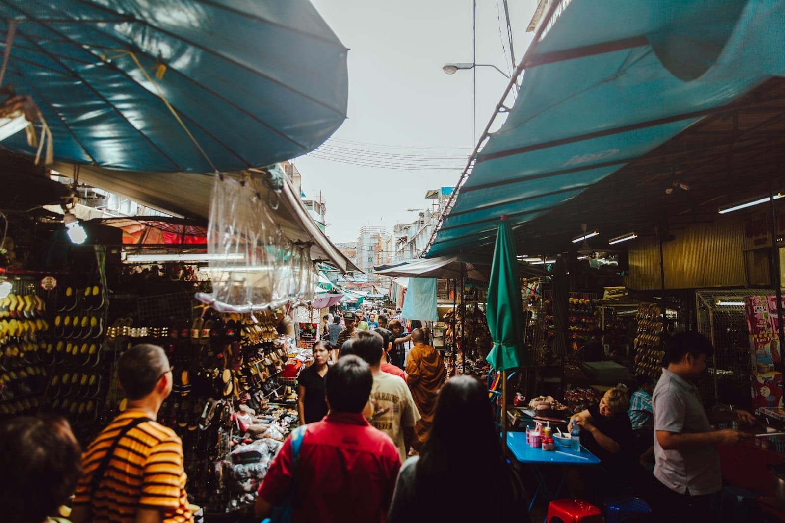 Mercado de rua lotado em Bangkok com compradores entre barracas cobertas por lonas