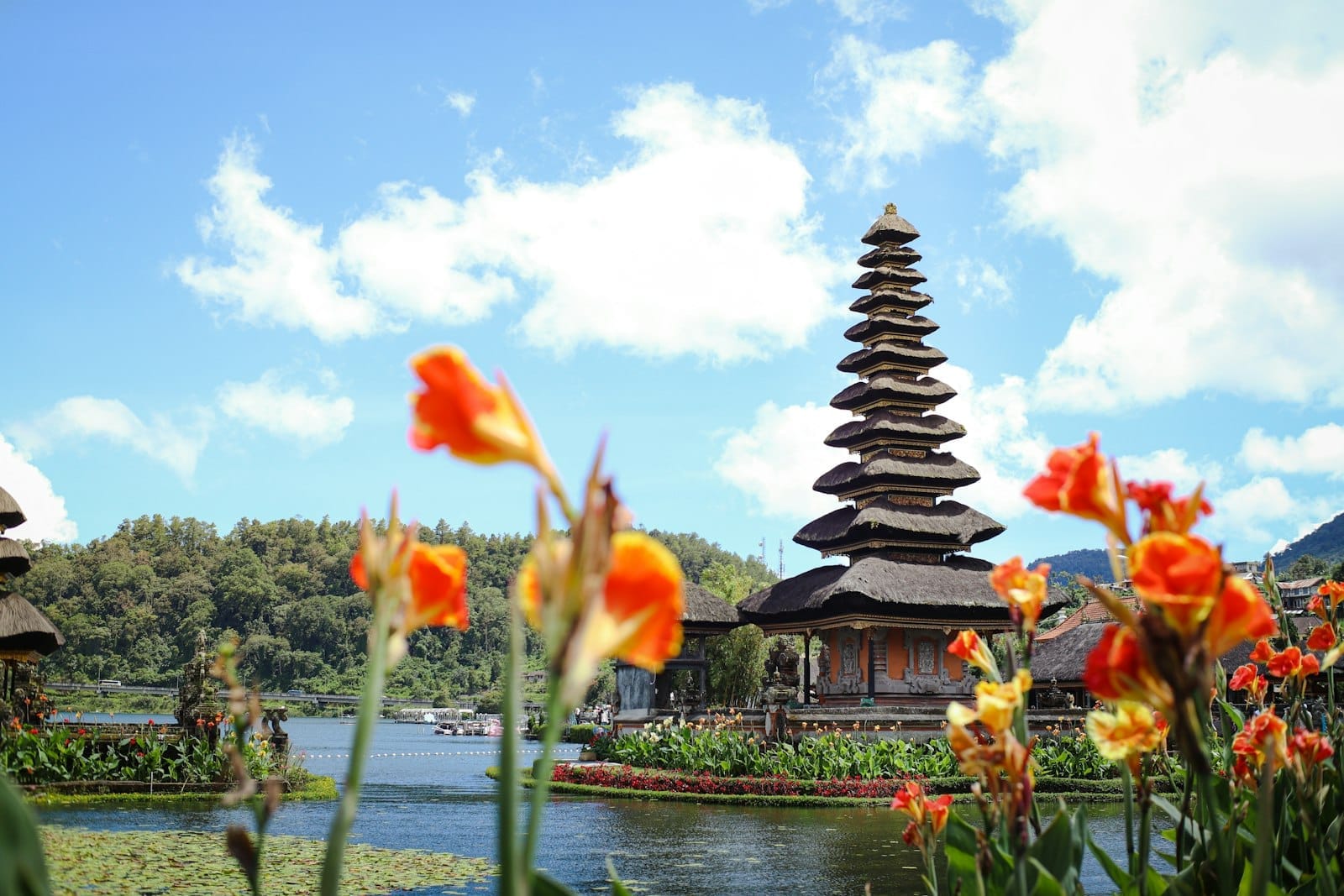 Templo Ulun Danu Beratan em Bali rodeado de flores e lago sob céu azul
