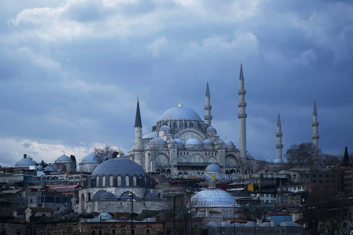 Vista de la gran Mezquita de Süleymaniye con múltiples minaretes elevándose sobre el paisaje urbano de Estambul bajo nubes dramáticas.