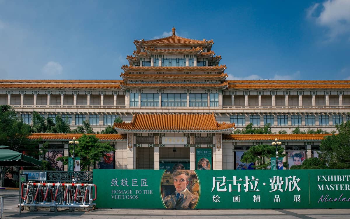 Frontansicht des Nationalmuseums Chinas in Peking mit einem großen traditionellen Dach und Bannern für eine Kunstausstellung.