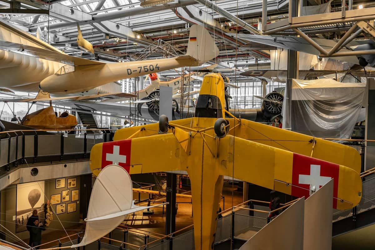 Innenansicht des Deutschen Technikmuseums Berlin mit Familien und Kindern, die bunte Flugzeuge und Ausstellungen in einer hellen, interaktiven Galerie erkunden.