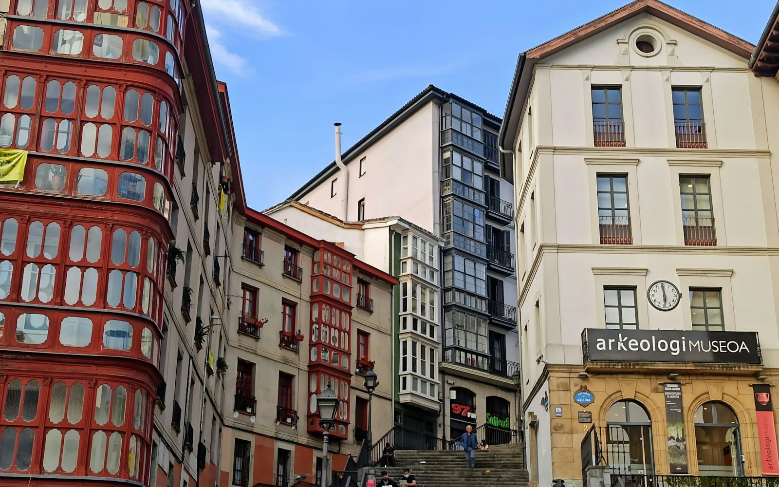 Wejście do Muzeum Archeologicznego w Bilbao w starym mieście, otoczone historycznymi baskijskimi budynkami i przechadzającymi się ludźmi.