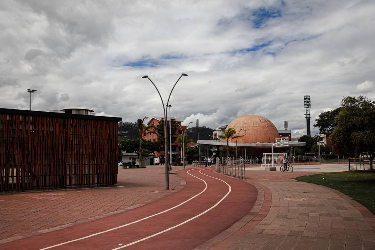 Wide plaza with distinctive orange-domed planetarium and modern urban park features under a cloudy sky in Bogotá.