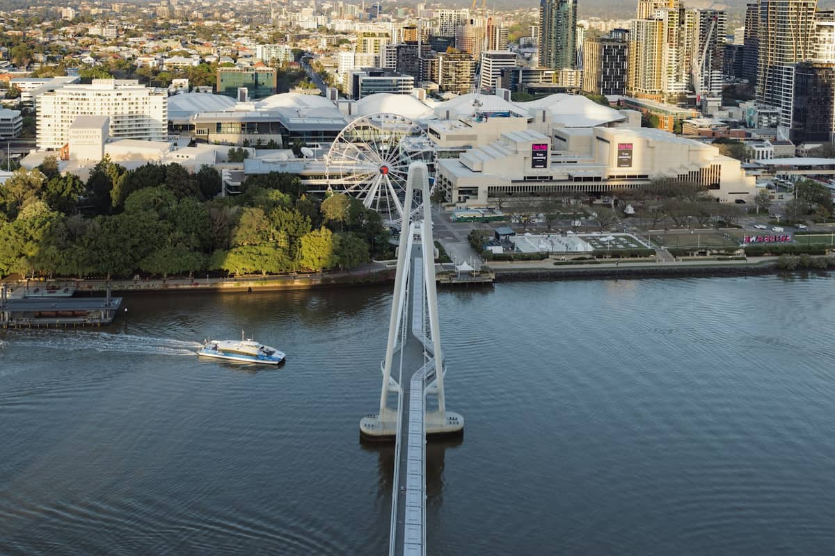 Widok z lotu ptaka na dzielnicę South Bank w Brisbane z Kołem Brisbane i białymi dachami Queensland Cultural Centre, gdzie nad rzeką mieszczą się główne muzea i galerie.