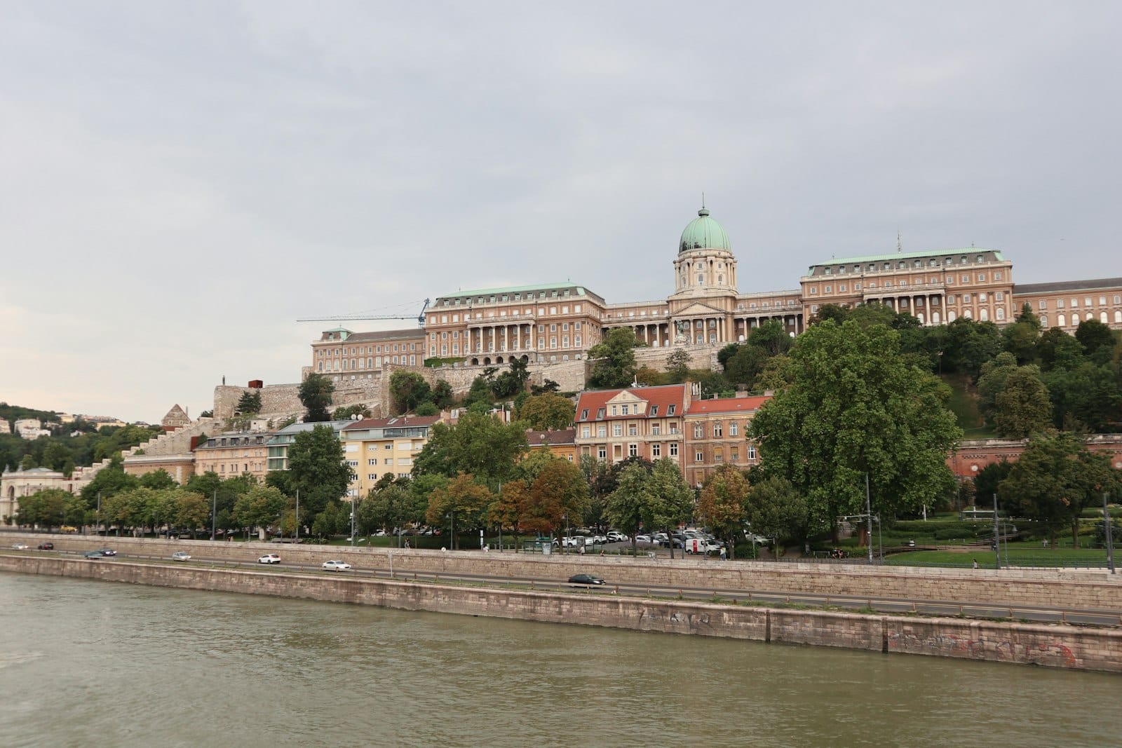 Tanawin sa araw ng Buda Castle sa Budapest mula sa kabilang ibayo ng ilog Danube, na nagpapakita ng iconic na dome at mga kapaligiran na makasaysayang gusali.