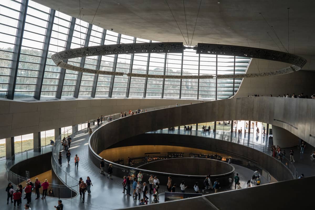 Innenraum des Sichuan-Museums in Chengdu mit Besuchern, die eine beeindruckende Spiralrampe unter einer Oberlichtkuppel entlanggehen.