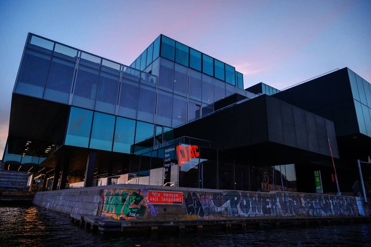 Efektowny nowoczesny szklany budynek nad nabrzeżem o zmierzchu, z odblaskowymi powierzchniami i współczesnymi liniami architektonicznymi w Kopenhadze.