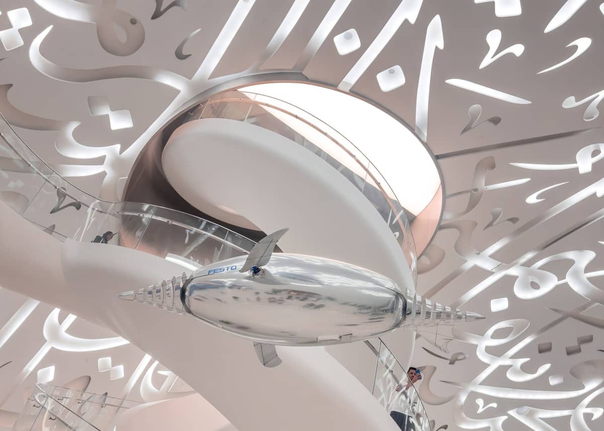 Futuristisches Innere des Museum of the Future in Dubai mit weißen skulpturalen Wänden, arabischer Kalligraphie und einer glänzenden metallischen Luftschiff-Installation.