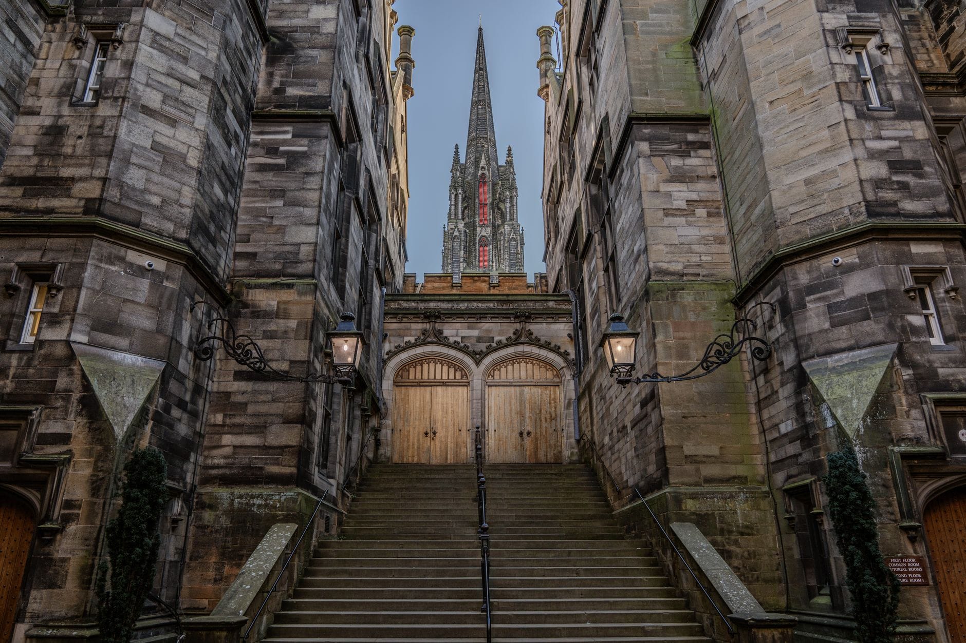 Atmosphärische Steintreppe, flankiert von historischen Gebäuden Edinburghs, mit dem Turm des Hub, der durch Bogentore oben zu sehen ist.